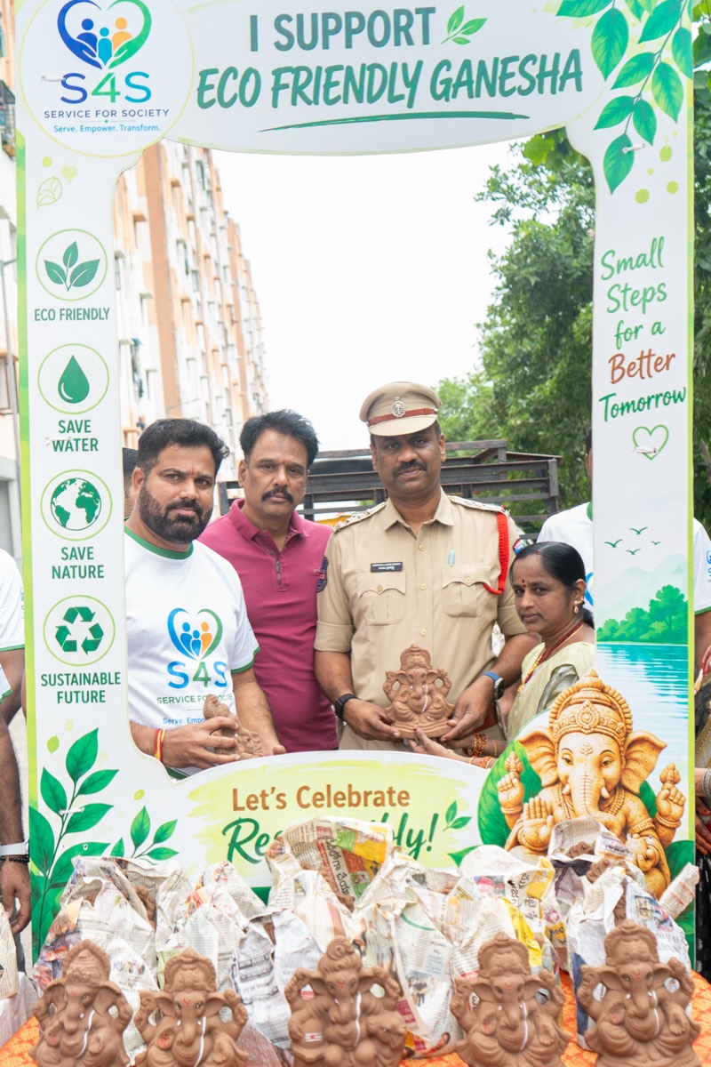 A police officer holding a natural clay Ganesha idol alongside volunteers